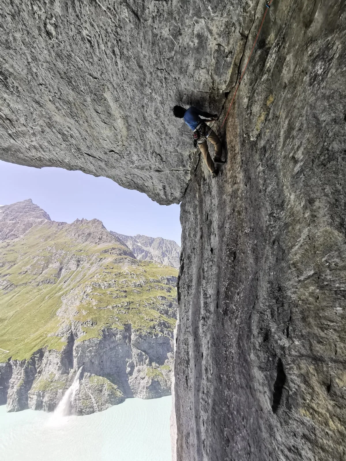 Un grimpeur progresse dans une paroi rocheuse au-dessus du vide